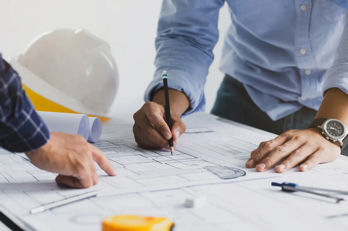 Bauleiter besprechen sich zu weiterem Vorgehen und markieren Informationen in Grundrissen